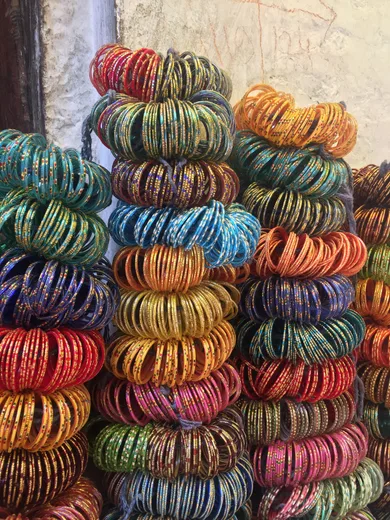 Stacks of colorful glass bangles against a whitewashed wall