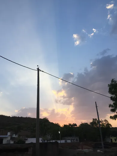 The sun setting over hills and a lake, seen through a wooden railing