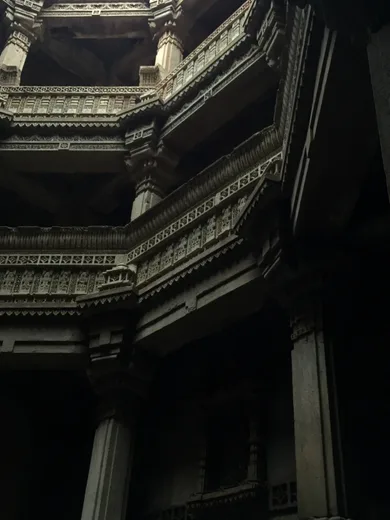 A stepwell balcony carved in stone, lit by dramatic side light
