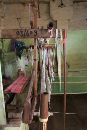 A handloom detail marked "03/609," yarn strung between wooden beams