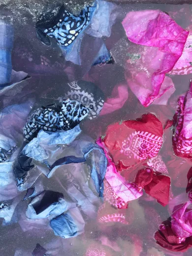 Tie-dyed bandhani fabric scraps soaking in a dye vat