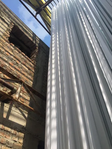 Pleated white fabric drying against a brick building under construction