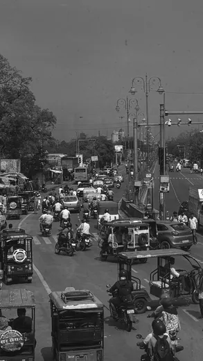 A black and white photo of a busy street with auto rickshaws