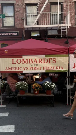 A red-awninged pizza stand on a brick-lined street