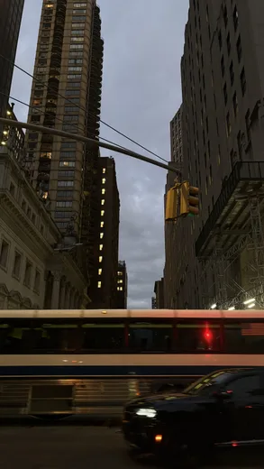City towers and a passing red bus seen from the street