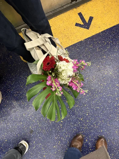A bouquet resting on a subway floor beside a yellow arrow