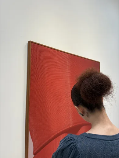 A woman seen from behind facing a large red painting