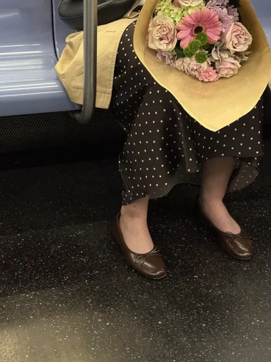 A woman on the subway holding a bouquet in yellow paper