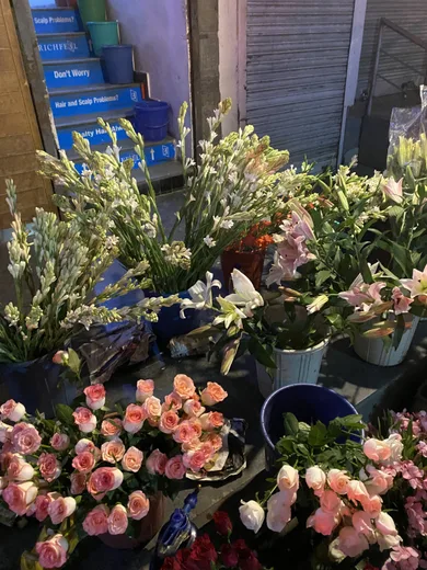 A flower stall piled with pink roses and white blooms