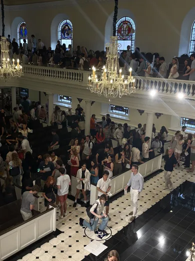 A crowded hall under chandeliers, seen from a balcony