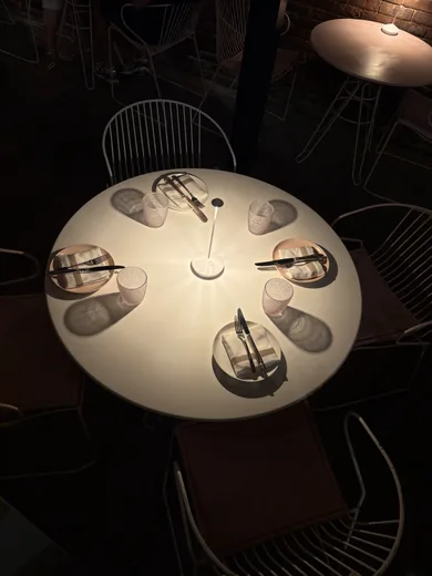 A round white table seen from above, ringed by chairs