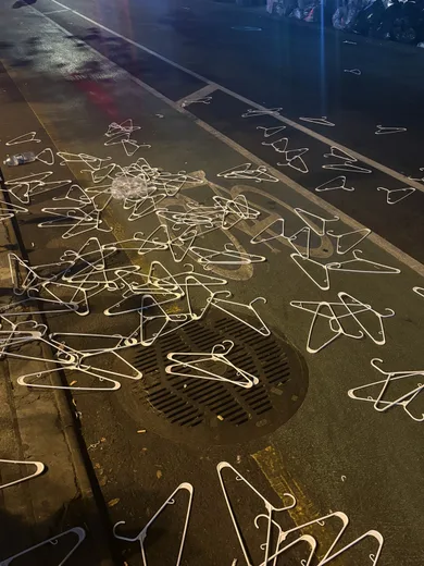 Chalk-like wire hangers scattered on a wet street