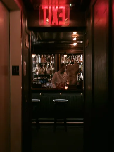 A dark doorway with a glowing red exit sign