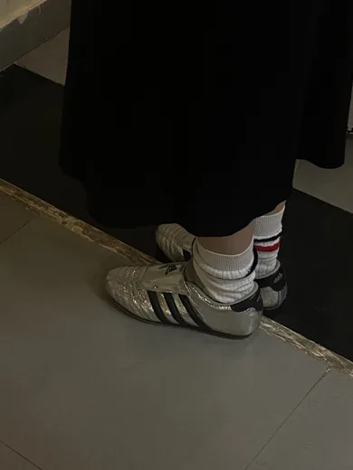 White sneakers and a black skirt on a grey floor