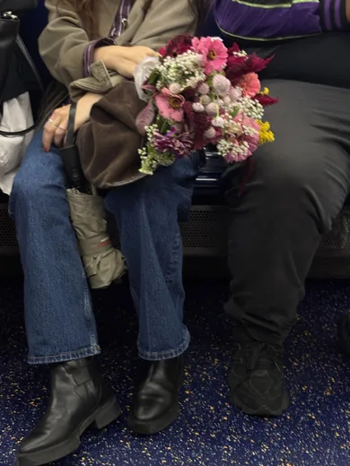 A bouquet held on the lap of a seated commuter