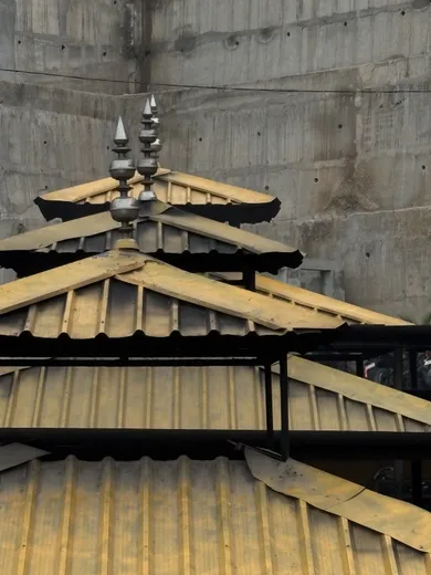 Layered golden pagoda-style roofs against a concrete wall