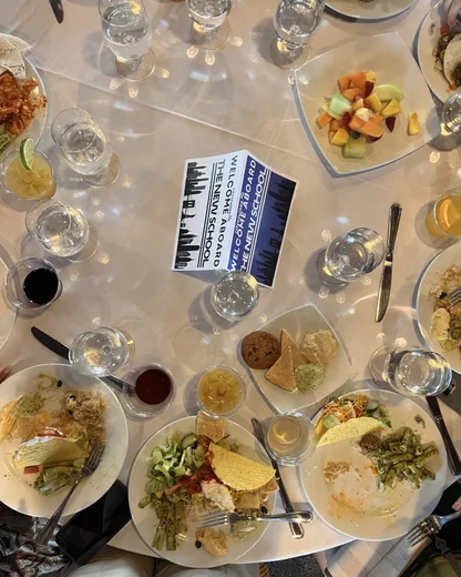 A table from above, covered in plates of food and a paperback
